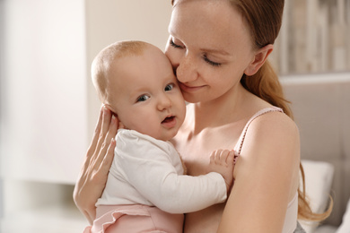 Photo of Young woman with her little baby resting after breast feeding in bedroom