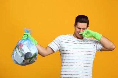 Man holding full garbage bag on yellow background