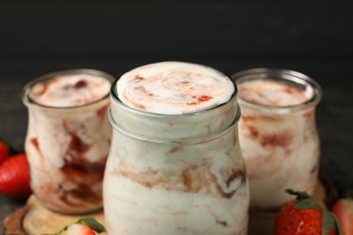 Photo of Tasty yoghurt with jam and strawberries on table, closeup