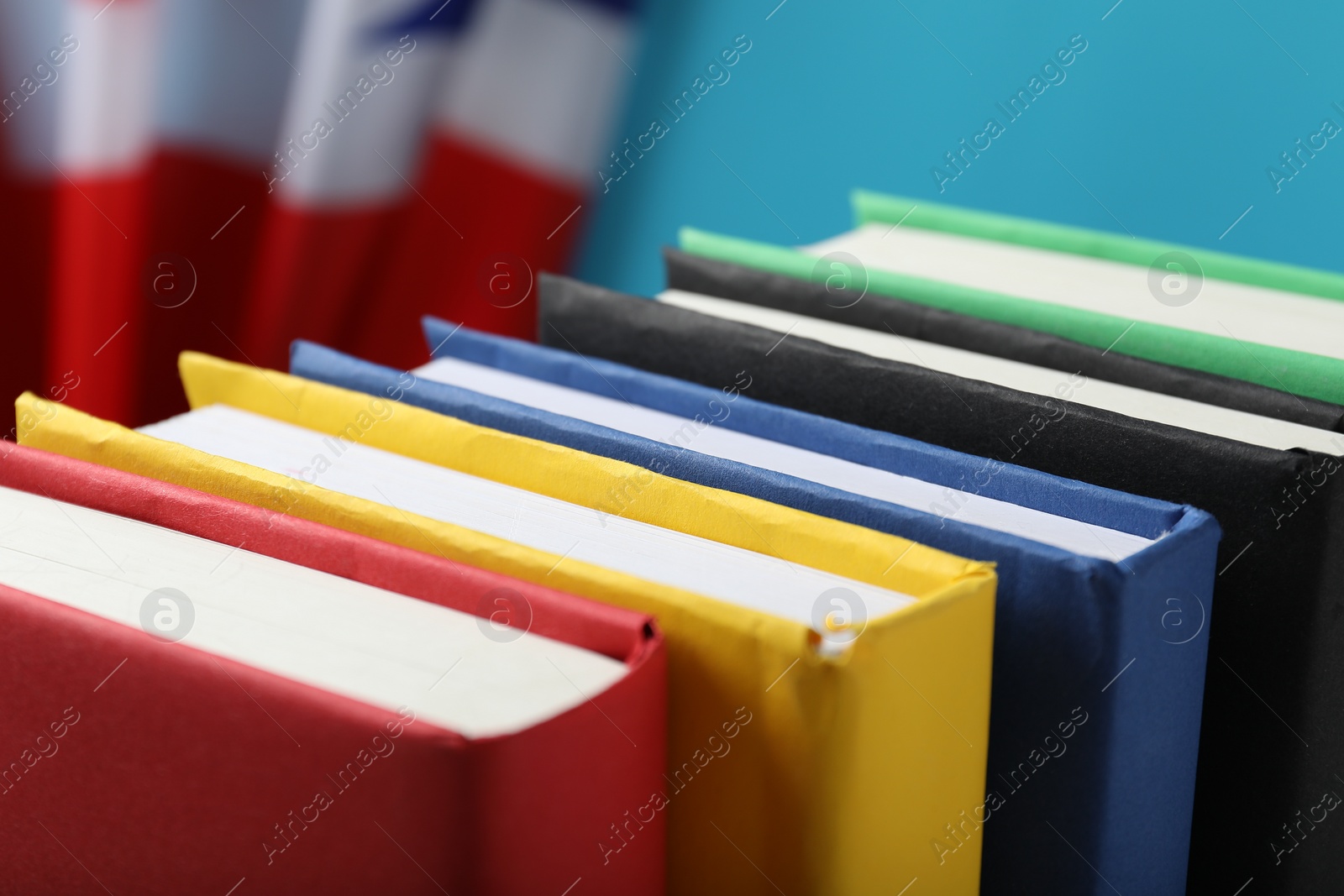 Photo of Learning foreign language. Different books and flag of United Kingdom on light blue background, closeup