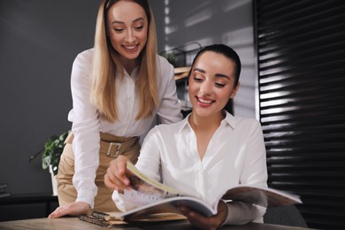 Photo of Happy young women with magazine in office