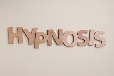 Word HYPNOSIS made with wooden letters on beige background, flat lay