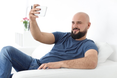 Photo of Portrait of young man taking selfie on sofa