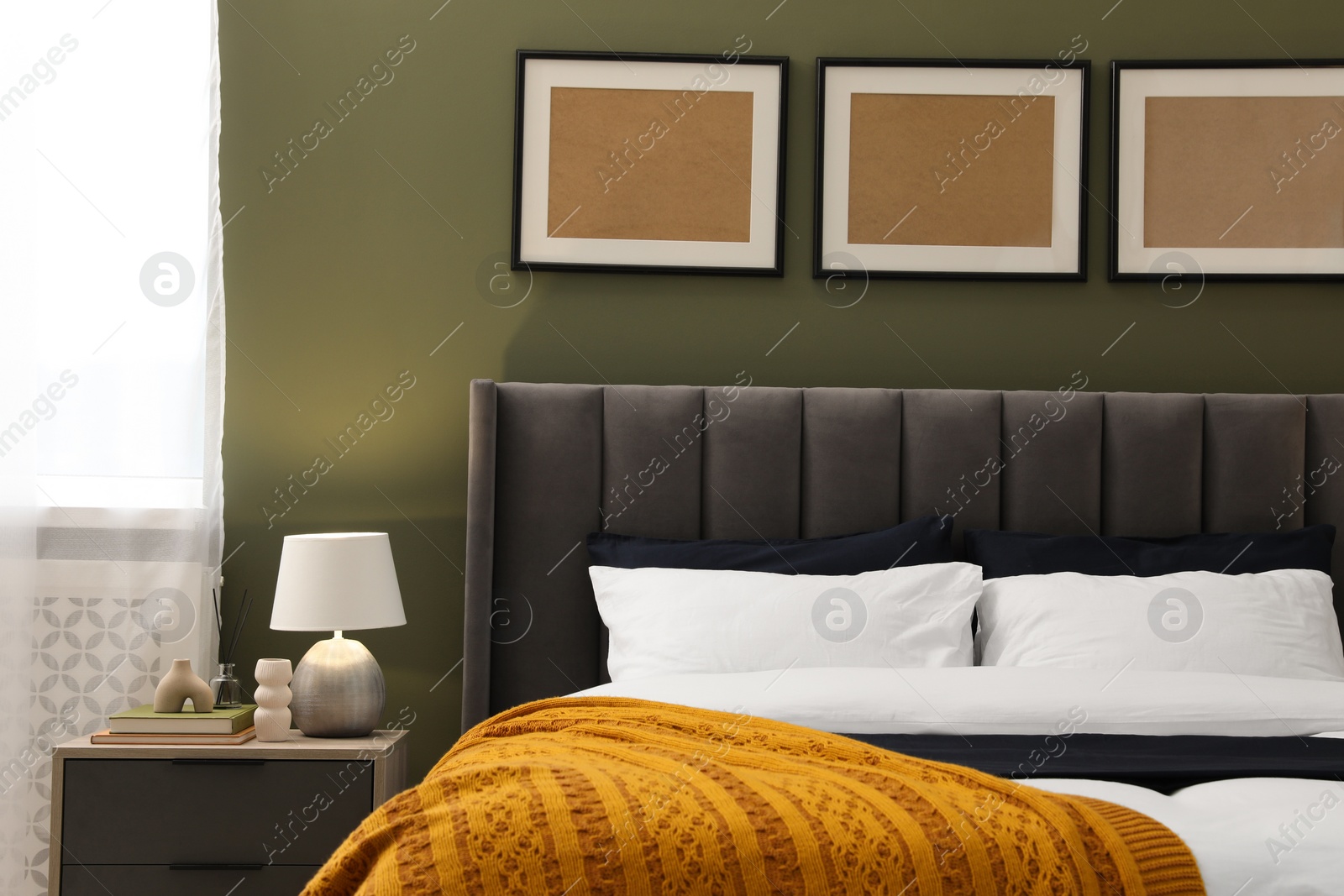 Photo of Large comfortable bed, nightstand and lamp in stylish room. Interior design