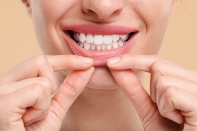 Photo of Woman showing her clean teeth on beige background, closeup