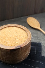 Photo of Brown sugar in bowl on grey table, closeup