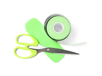 Photo of Scissors, bright kinesio tape roll and piece on white background, top view