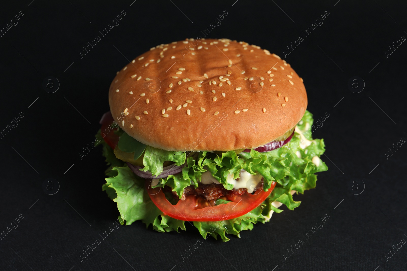 Photo of Delicious burger with beef patty and lettuce on black background