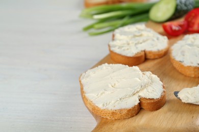 Toasted bread with cream cheese on white wooden table, closeup. Space for text