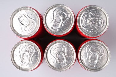 Photo of Energy drinks in wet cans on light grey background, top view