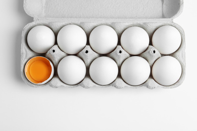 Photo of Fresh chicken eggs in box on white background, top view