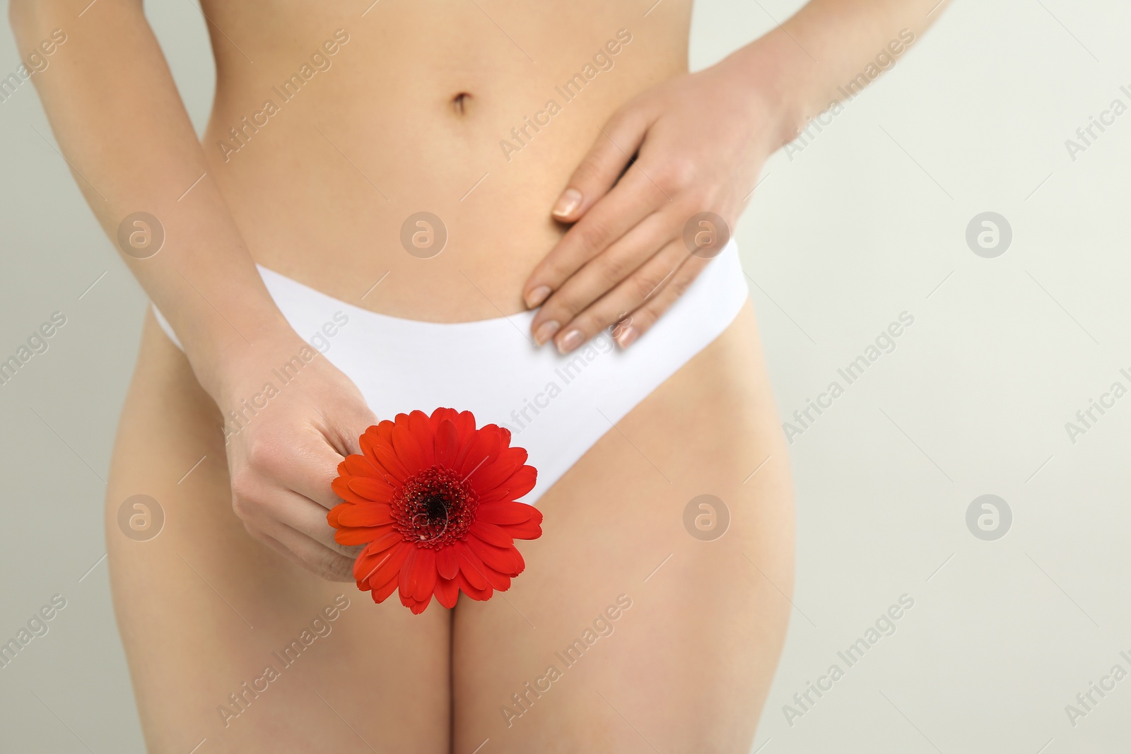 Photo of Gynecology. Woman in underwear with gerbera flower on light background, closeup