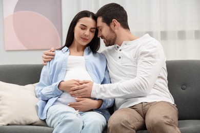 Photo of Pregnant woman with her husband on sofa at home