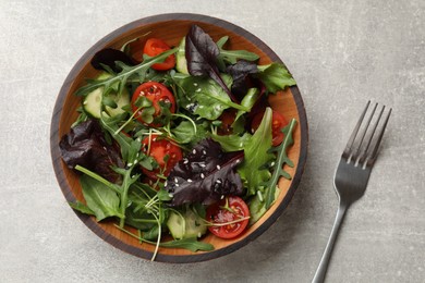 Tasty fresh vegetarian salad and fork on grey table, top view