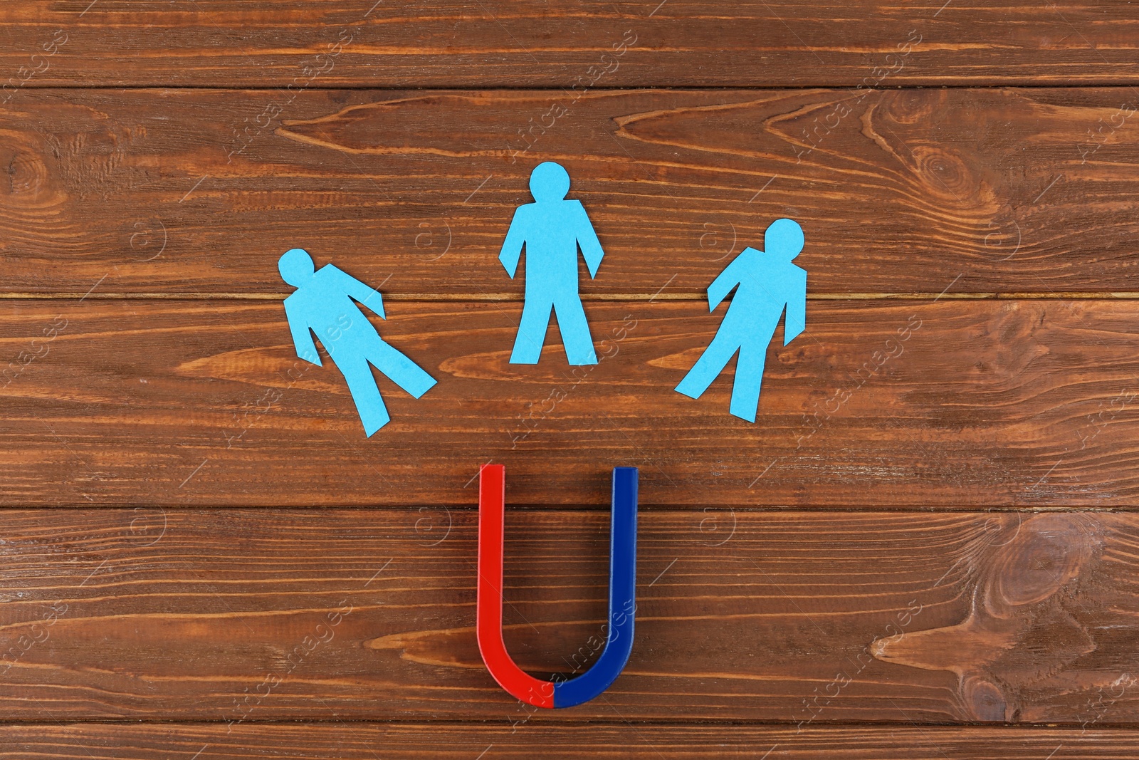 Photo of Magnet and paper people on wooden table, flat lay