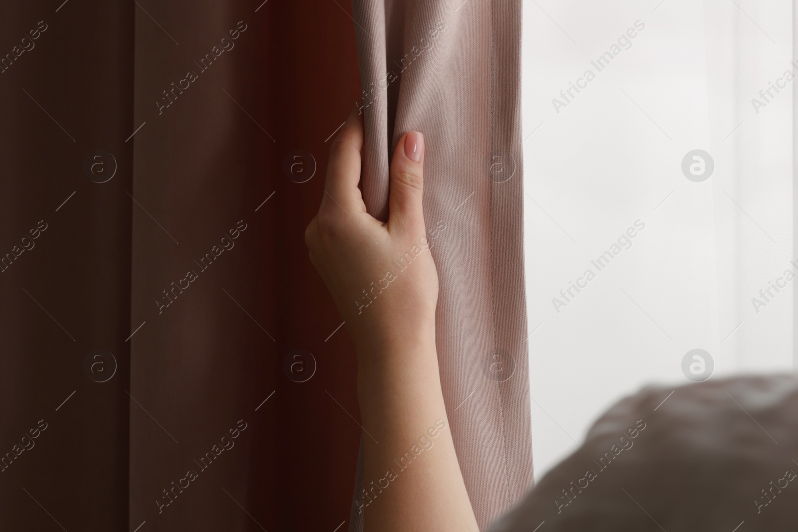 Photo of Woman opening stylish curtains at home, closeup