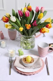Photo of Festive table setting with painted egg in decorative nest. Easter celebration
