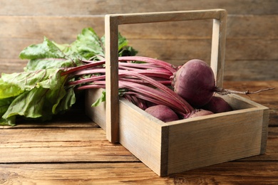 Photo of Raw ripe beets in basket on wooden table