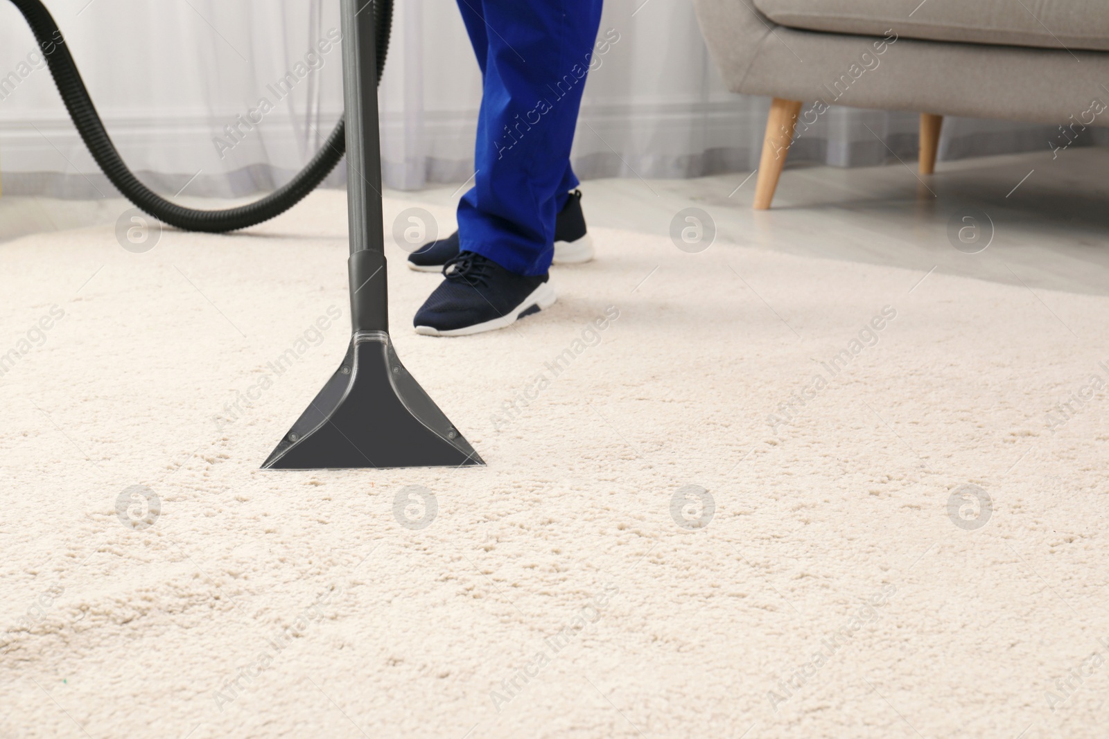 Photo of Man removing dirt from carpet with vacuum cleaner indoors, closeup. Space for text