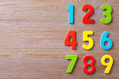 Photo of Colorful numbers on wooden table, flat lay. Space for text