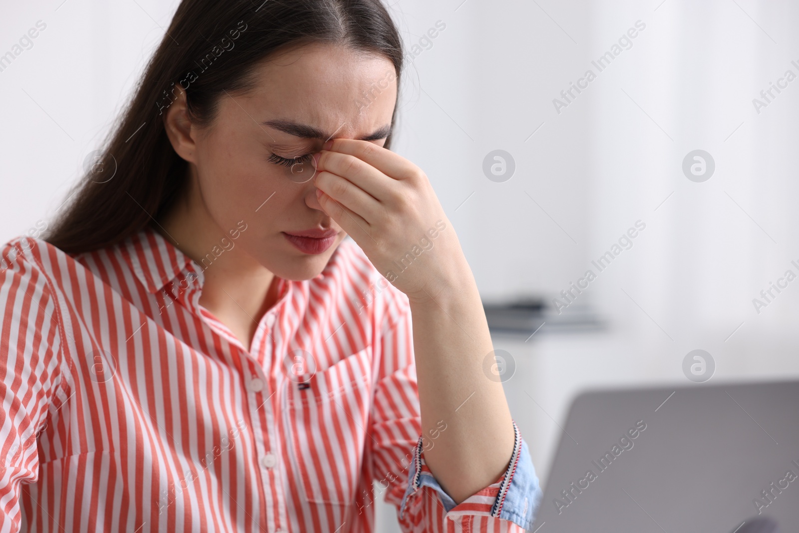 Photo of Woman suffering from headache at workplace in office