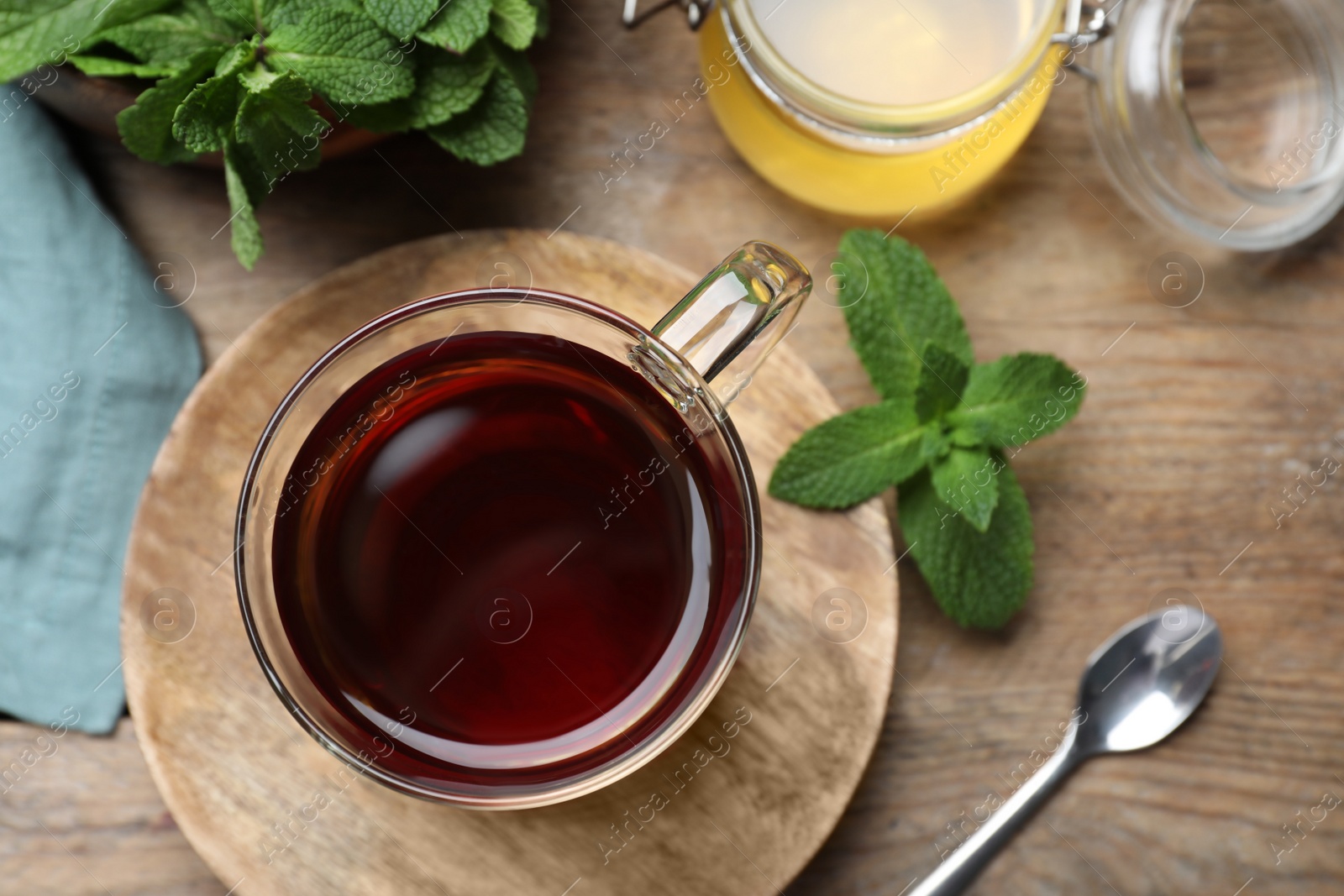 Photo of Cup of hot aromatic tea with mint and honey on wooden table, flat lay