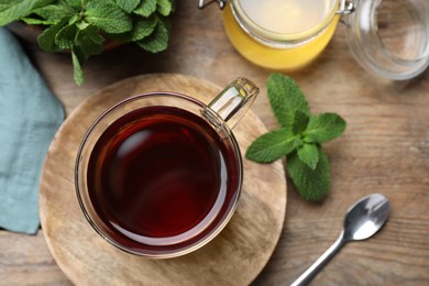 Cup of hot aromatic tea with mint and honey on wooden table, flat lay