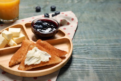 Photo of Tasty toasts with butter and blueberries on light blue wooden table, closeup. Space for text