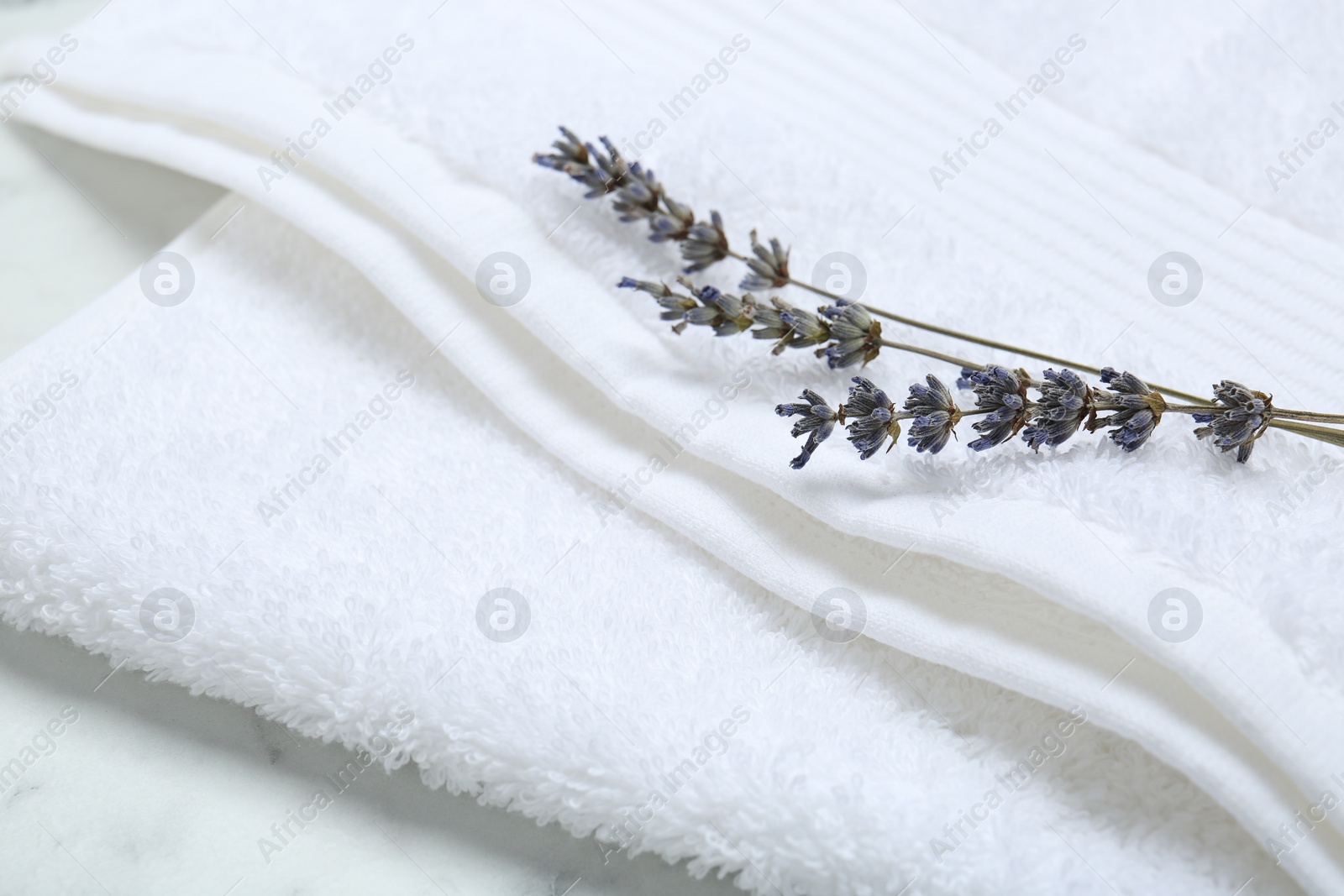 Photo of Terry towel and dry flowers on white table, closeup