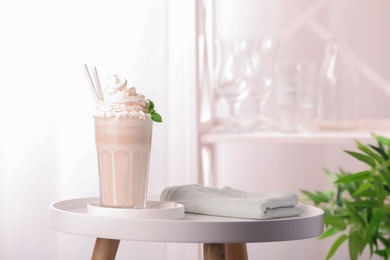 Glass with delicious milk shake on table