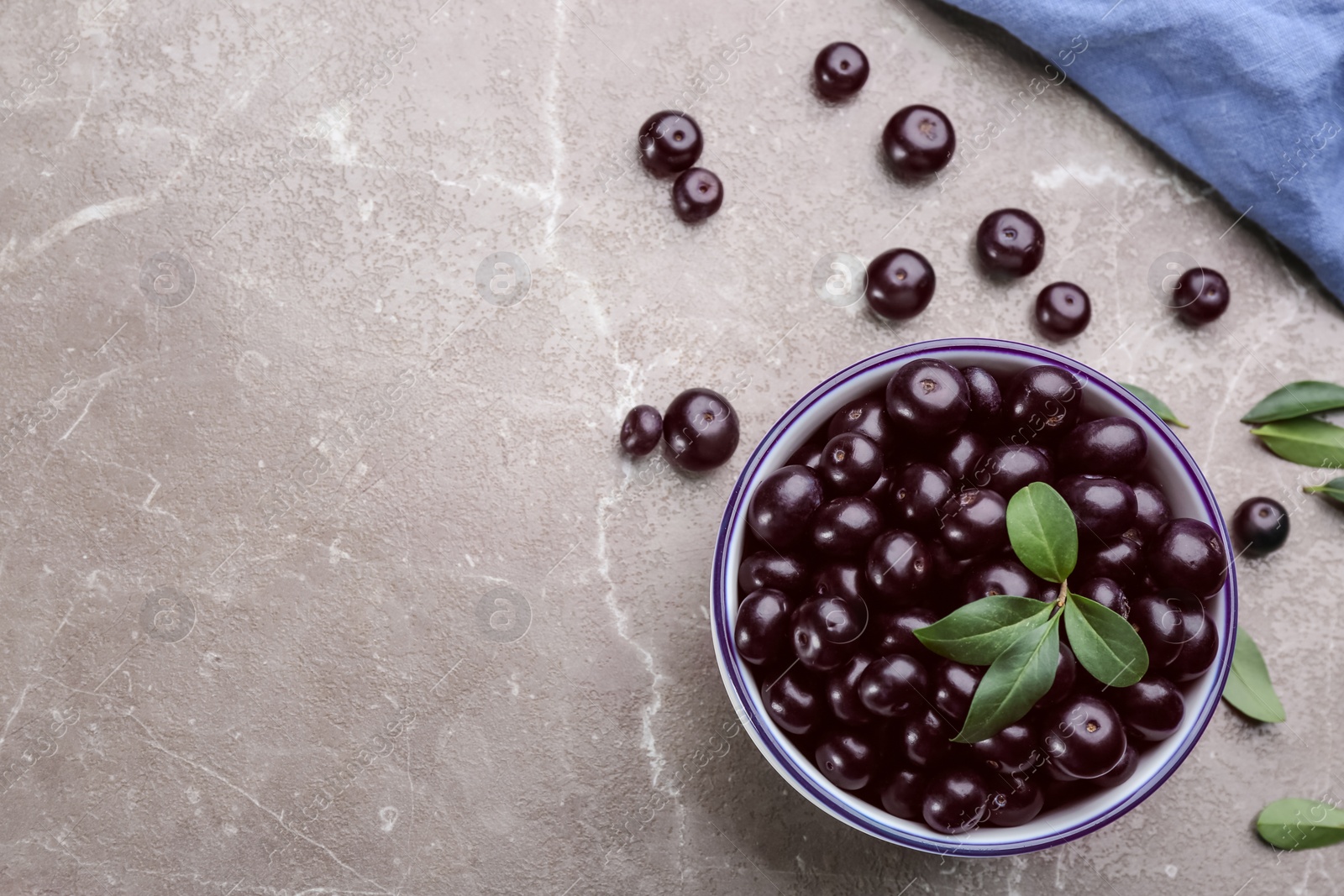 Photo of Fresh acai berries in bowl on light marble table, flat lay. Space for text