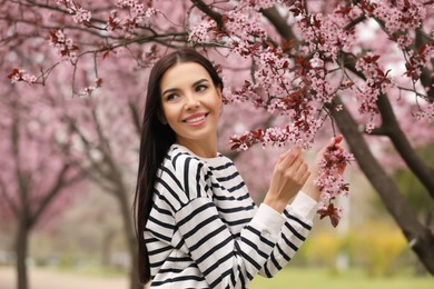 Photo of Pretty young woman near blooming tree in park. Spring look