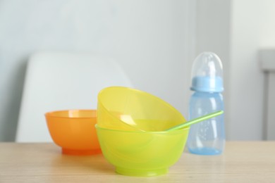 Photo of Set of plastic dishware on wooden table indoors. Serving baby food