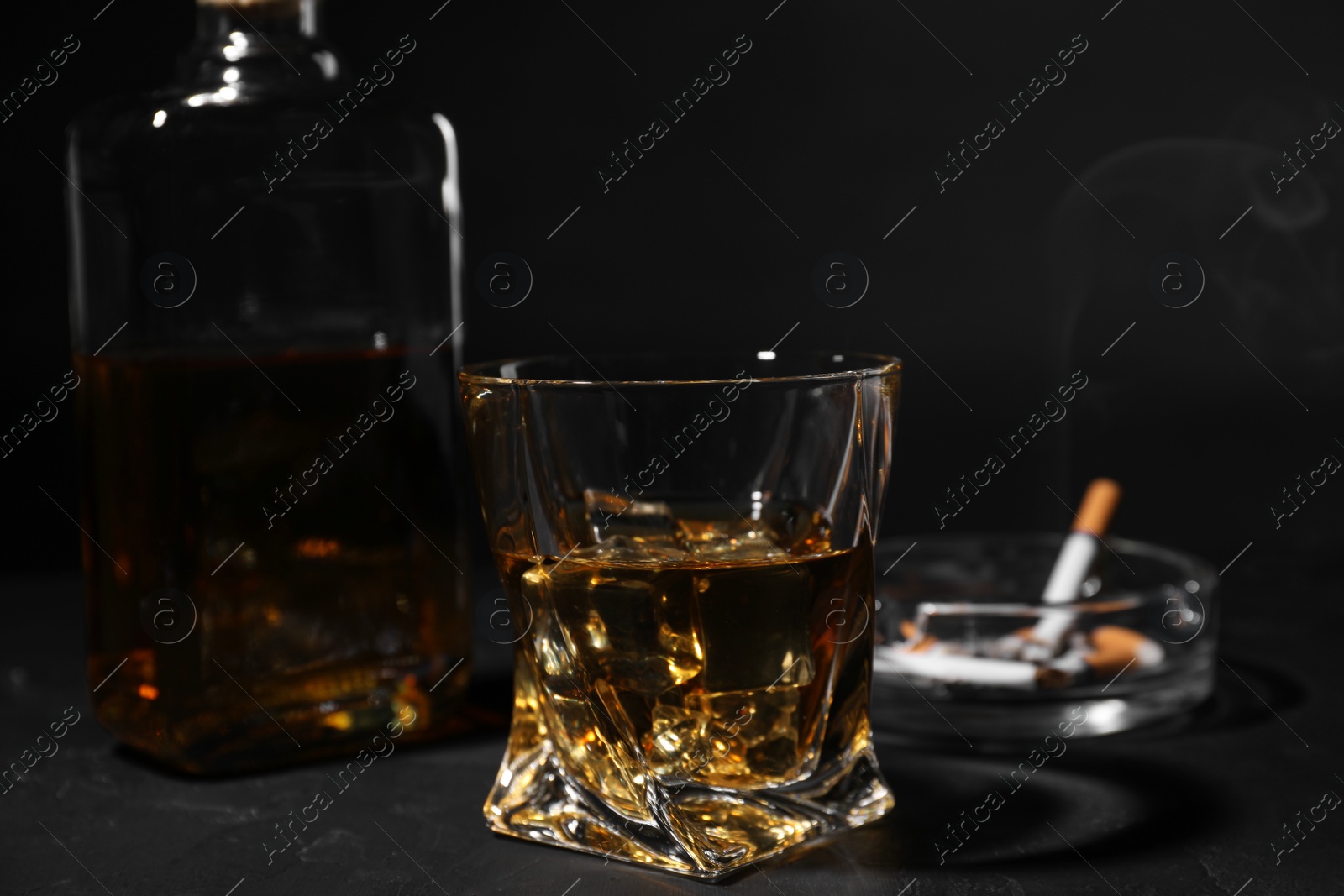 Photo of Alcohol addiction. Whiskey in glass on dark textured table, closeup