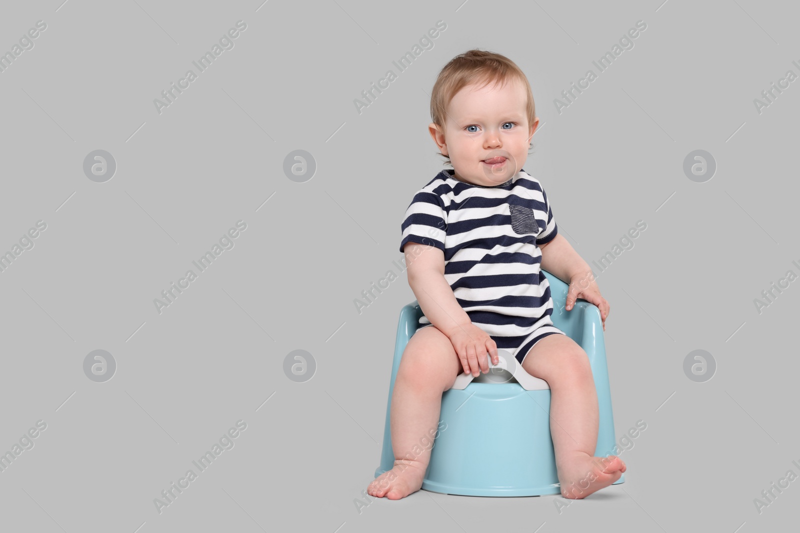 Photo of Little child sitting on baby potty against light grey background, space for text