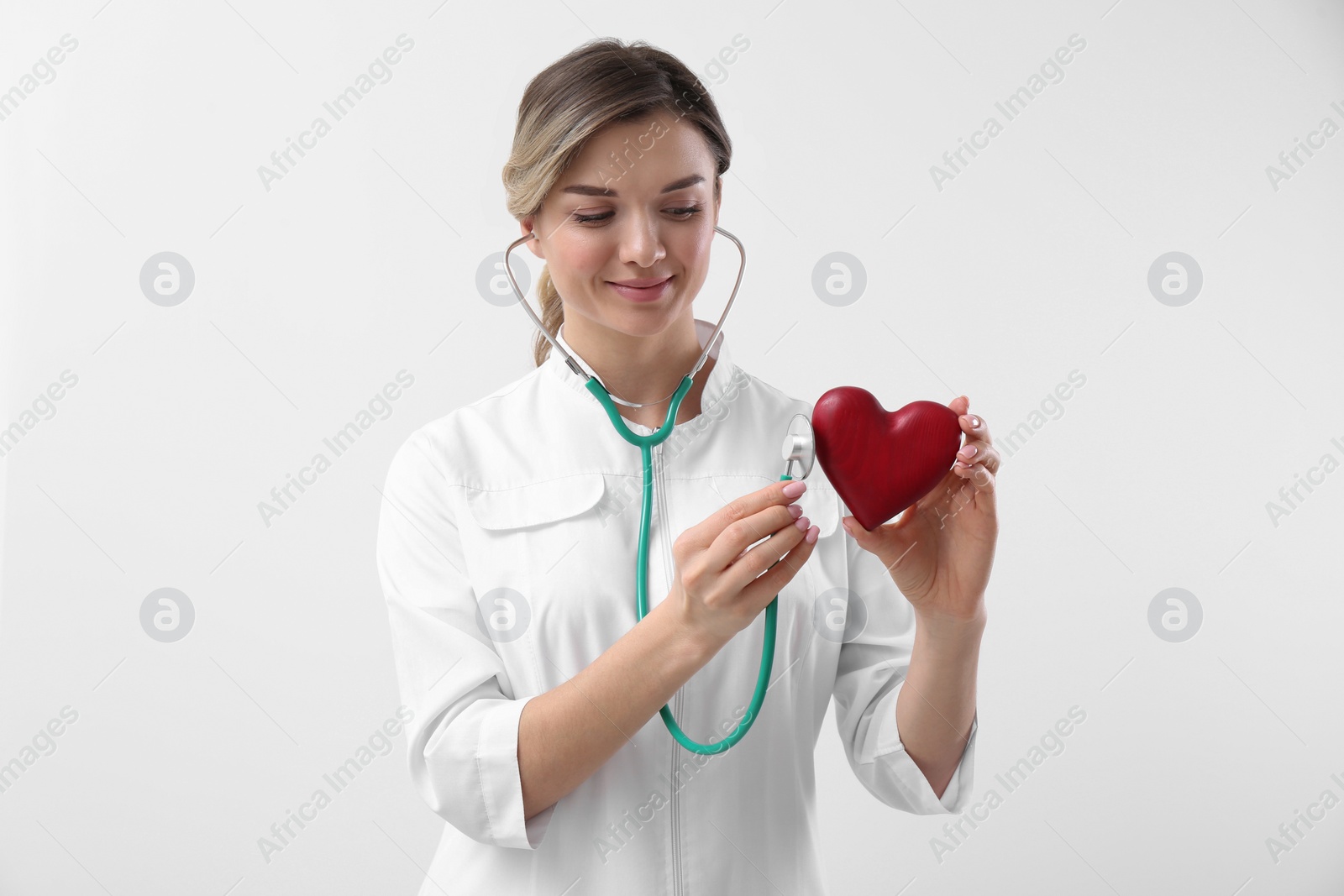 Photo of Doctor with stethoscope and red heart on white background. Cardiology concept