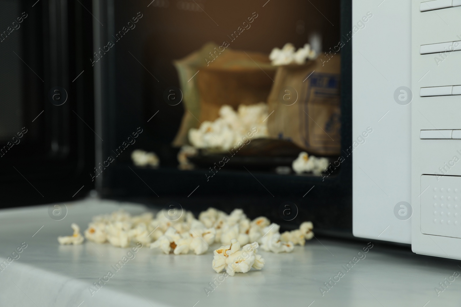 Photo of Open microwave oven with fresh popcorn on table, closeup