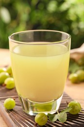 Photo of Tasty gooseberry juice and fresh berries on wooden board, closeup