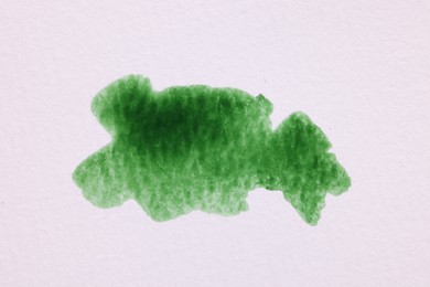 Blot of green watercolor paint on white paper, top view