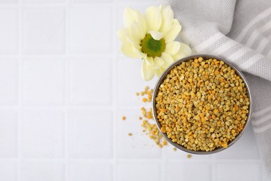 Photo of Fresh bee pollen granules and flower on white table, top view. Space for text