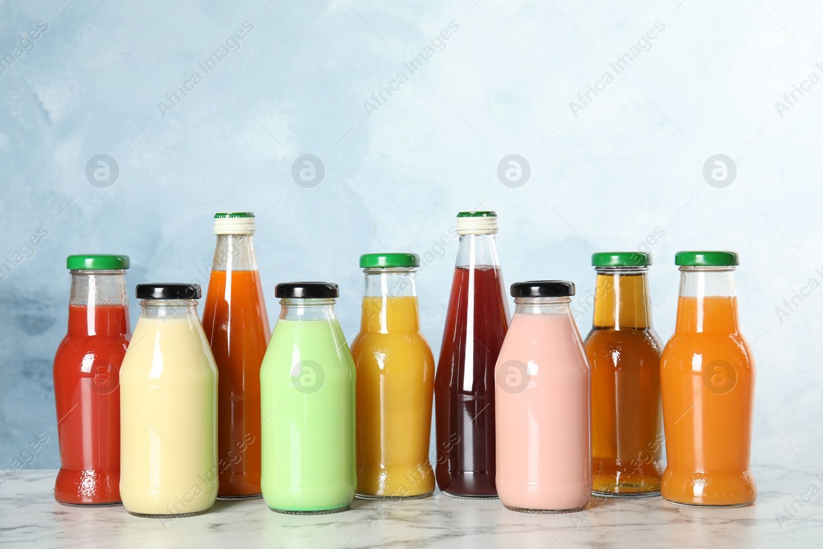 Photo of Bottles with different drinks on table against color background