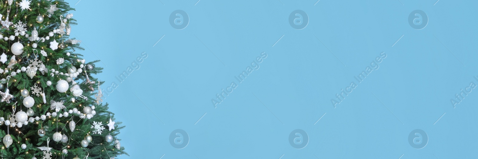 Image of Beautifully decorated Christmas tree on light blue background, space for text. Banner design