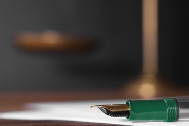 Photo of Fountain pen and paper document on table, closeup with space for text. Notary service