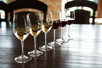 Photo of Glasses of white and red wines on wooden table