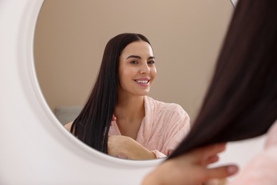 Photo of Beautiful young woman near mirror at home