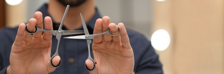 Image of Hairstylist holding professional scissors in beauty salon, closeup. Banner design