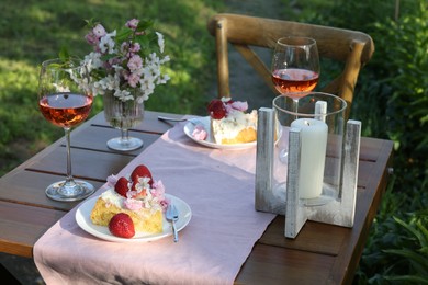 Photo of Vase with spring flowers, wine and cake on table served for romantic date in garden