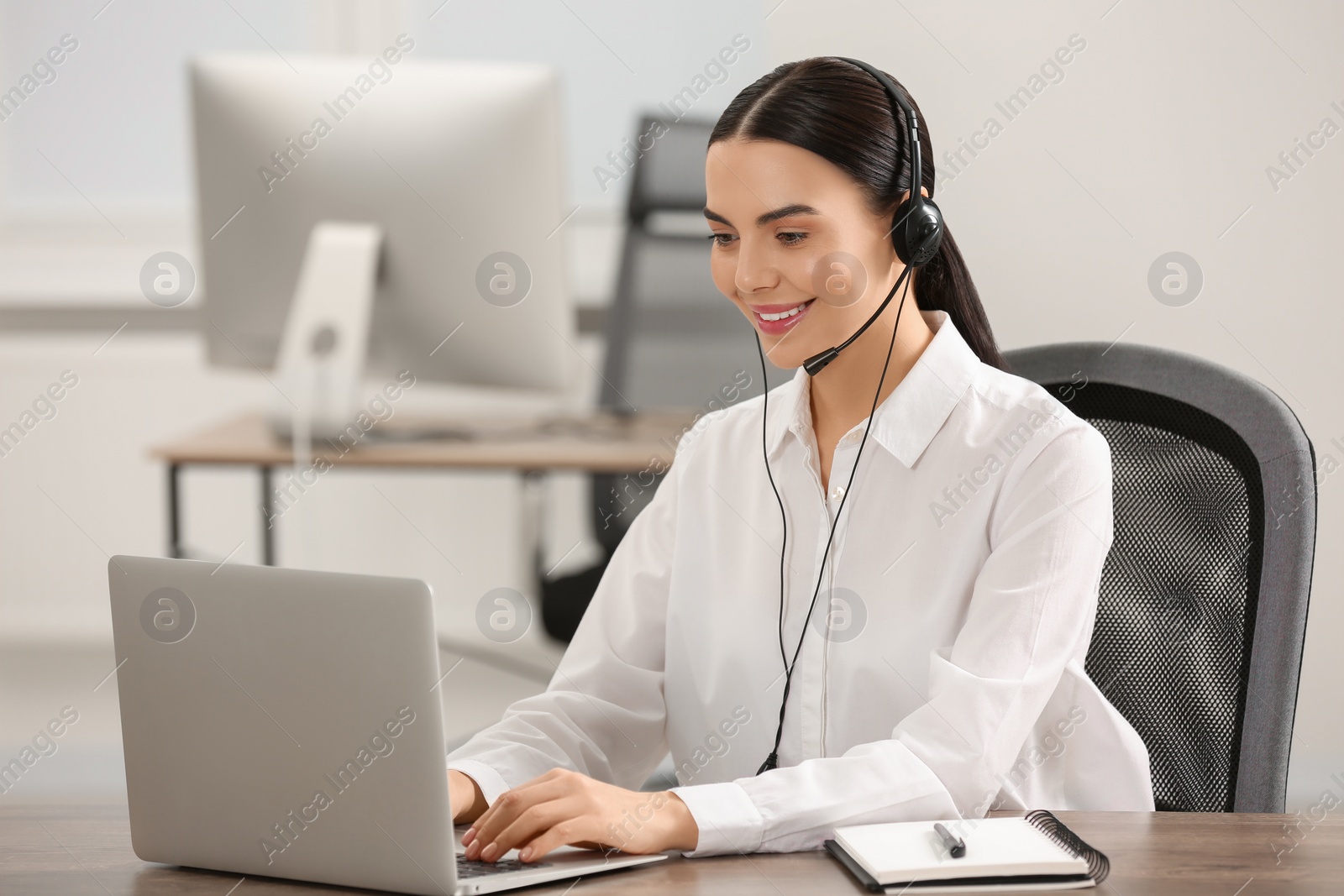 Photo of Hotline operator with headset working on laptop in office