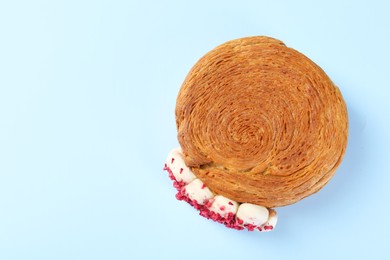 Photo of One supreme croissant with cream on light blue background, top view with space for text. Tasty puff pastry