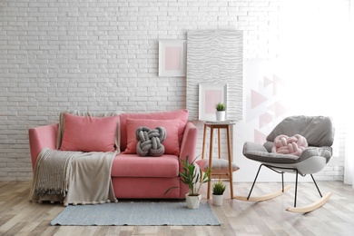 Photo of Stylish living room interior with sofa and rocking armchair near brick wall. Space for text